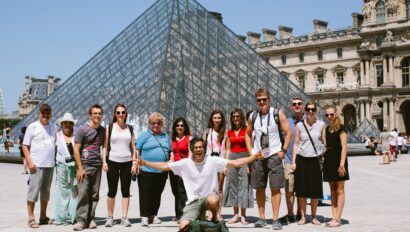 A group poses for a photo in front of the Louvre Pyramid in Paris, France