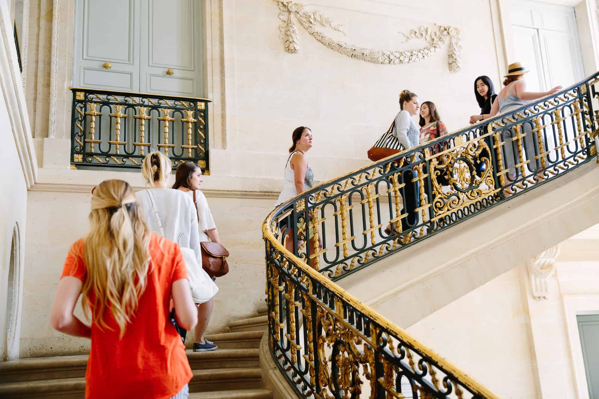 A group climbs the stairs inside the palace of Versailles.