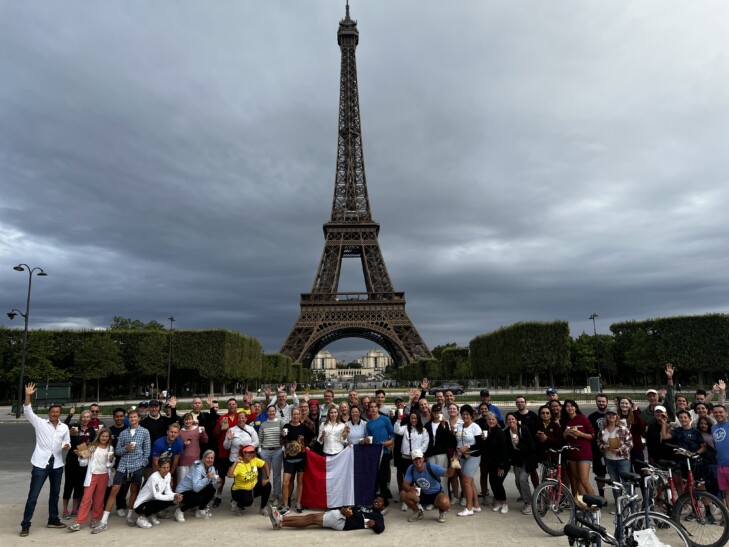 A group poses in front of the eiffel tower after their tour de france ride