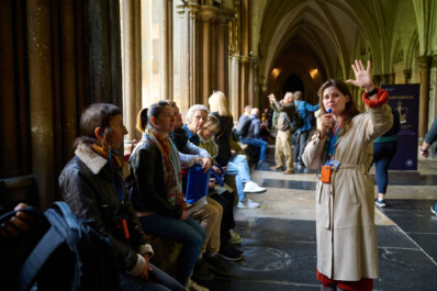 A guide talks to a group as they sit inside Westminster Abbey