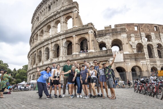 A group poses for a photo in front of the Colosseum in Rome, Italy