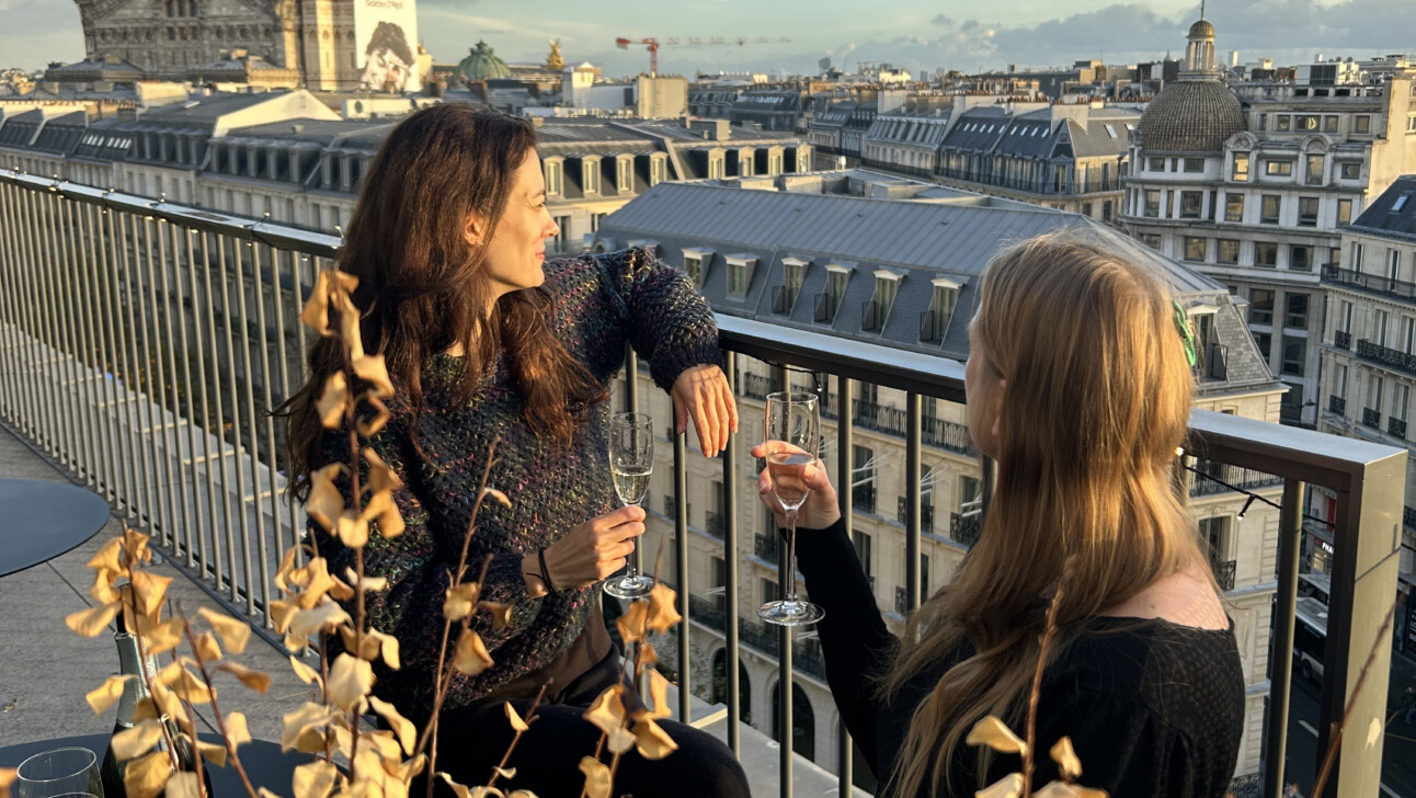 Two friends drink champagne with a view of Paris at sunset