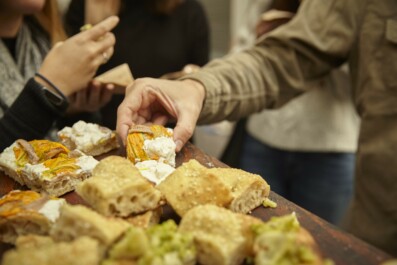 People trying bread and cheese from a shared plate in Italy