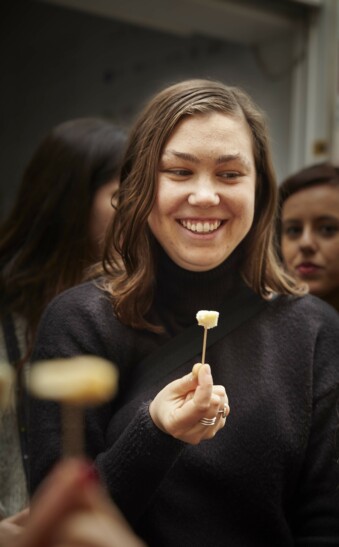 A woman with a small piece of cheese on a toothpick