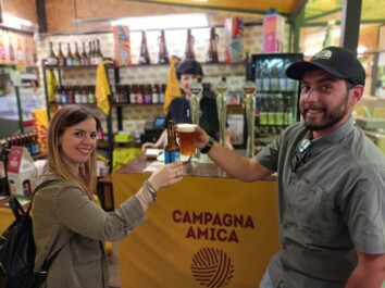 A couple cheers with beer at a market in Rome, Italy