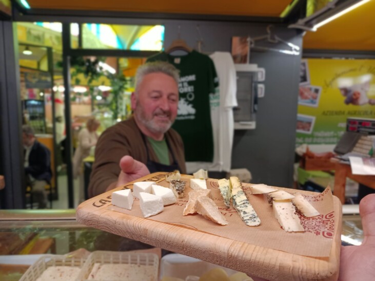 A cheese monger hands over a tasting plate of cheese