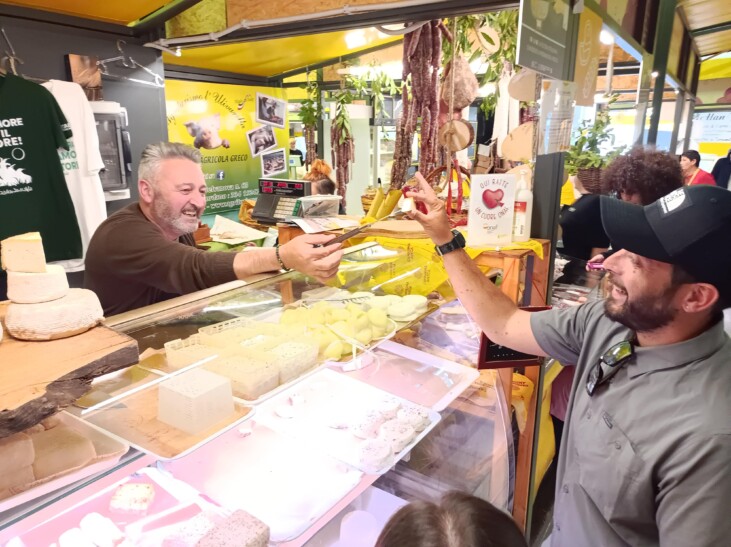 A man tries a piece of cheese from the end of a knife at a market in Rome, Italy