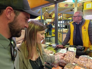 A couple looks at a package of nuts at a market stall in Rome, Italy