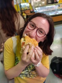 A woman takes a big bite out of a sandwich
